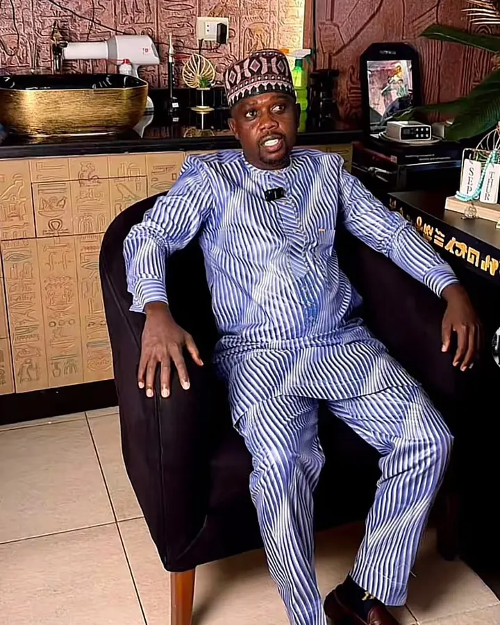 Chérif Moussa, assis dans un fauteuil, en tenue traditionnelle rayée bleue